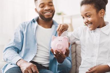Image of father and daughter with piggy bank